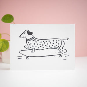 sausage roll sausage dog on a skateboard lino print card